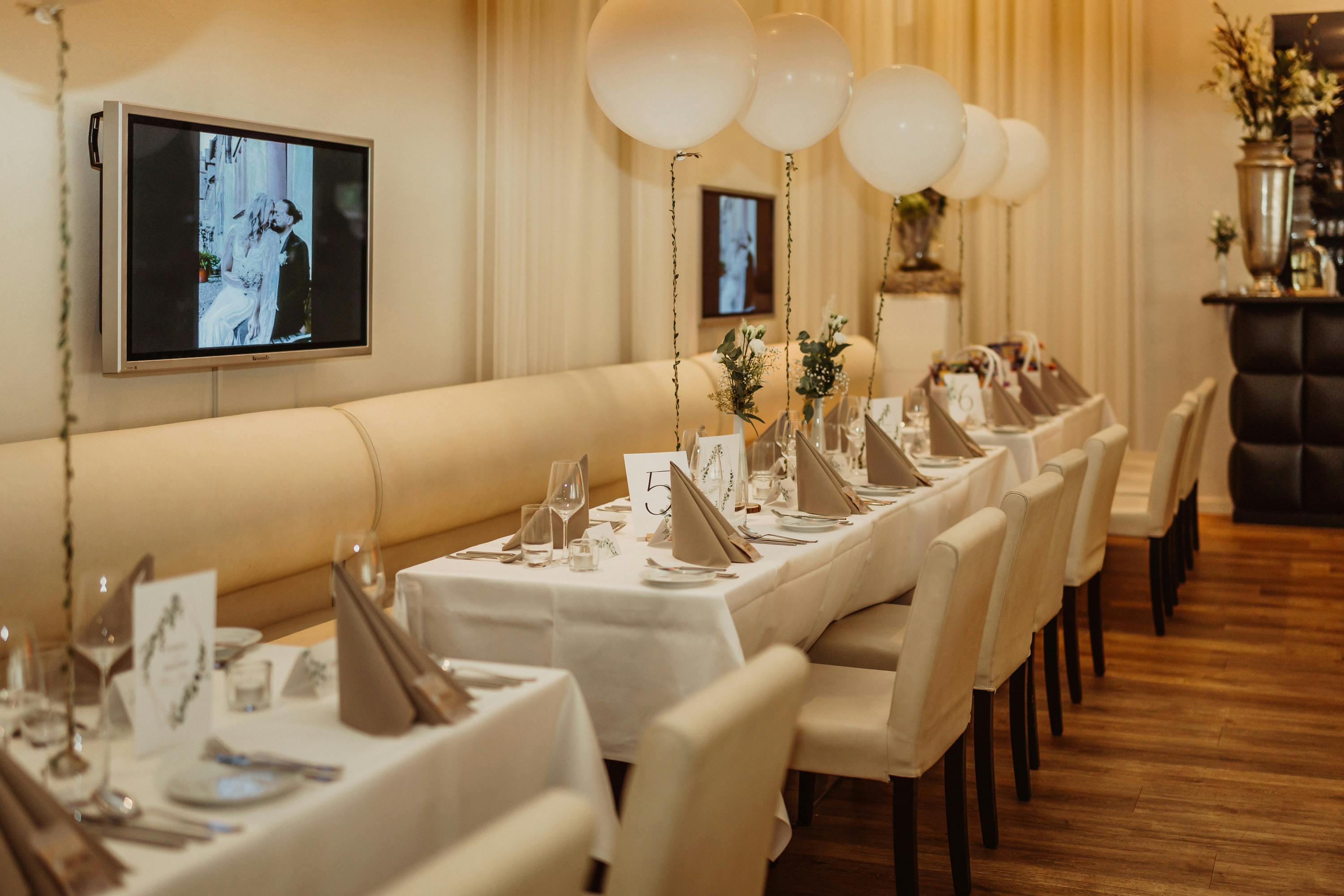 Stylish restaurant interior with decorated tables and white balloons, ready for a special ceremony.
